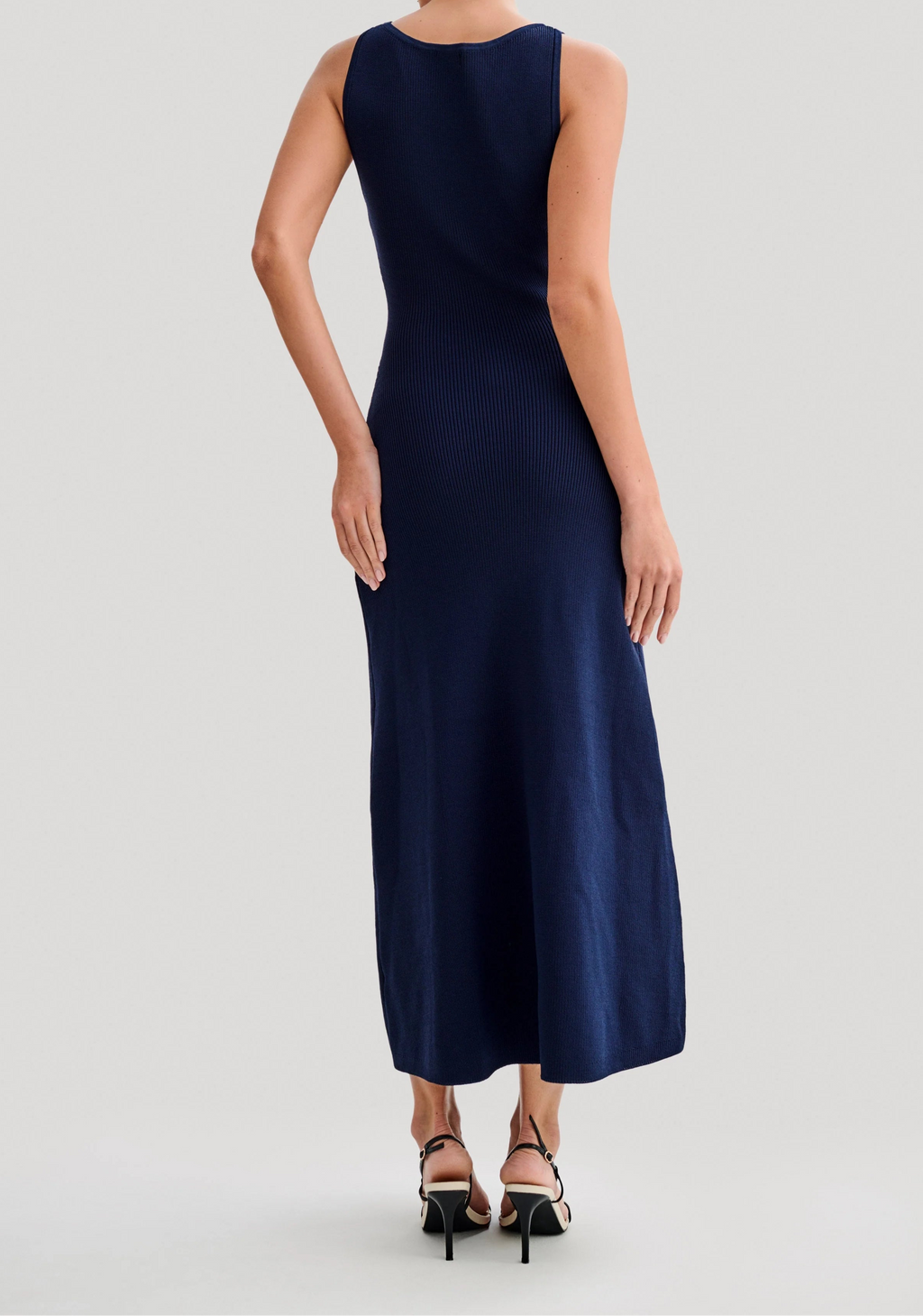 Woman wearing a navy blue dress on a light gray background