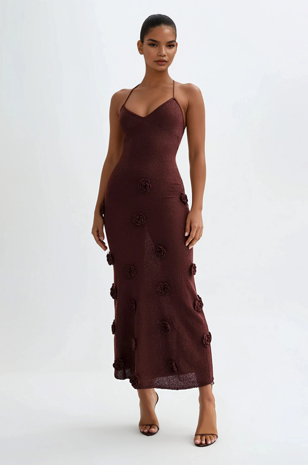 Woman wearing a brown dress with floral details on a white background