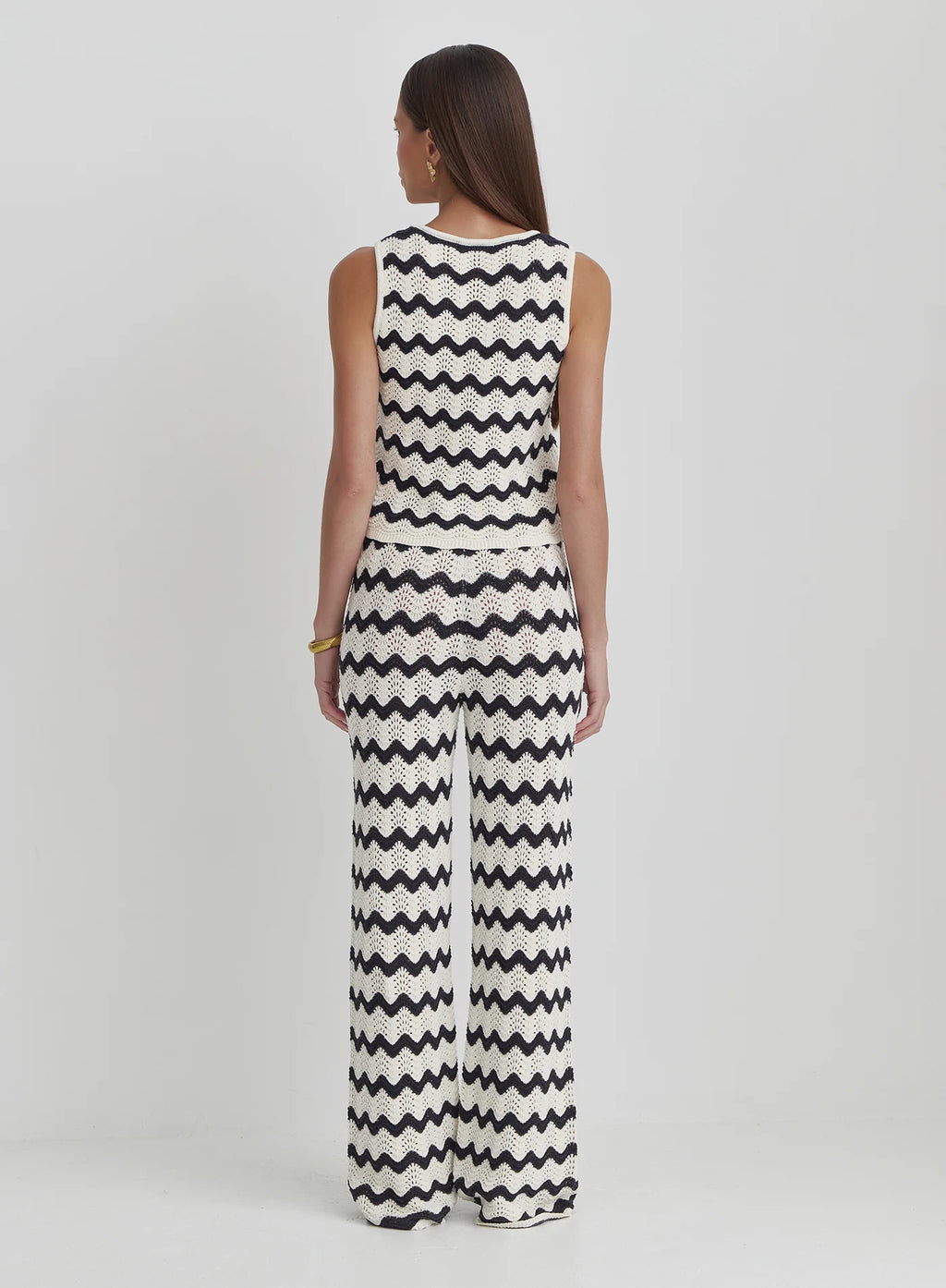 Woman wearing a black and white zigzag patterned jumpsuit on a white background