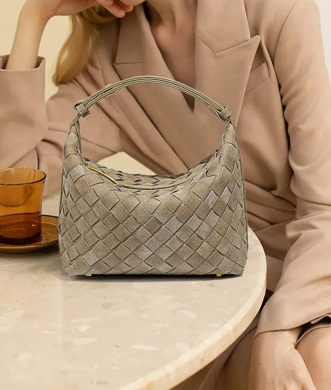Woman holding a woven handbag with a neutral background