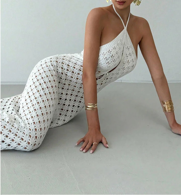 Woman in a white dress with gold patterns sitting on a light gray floor.