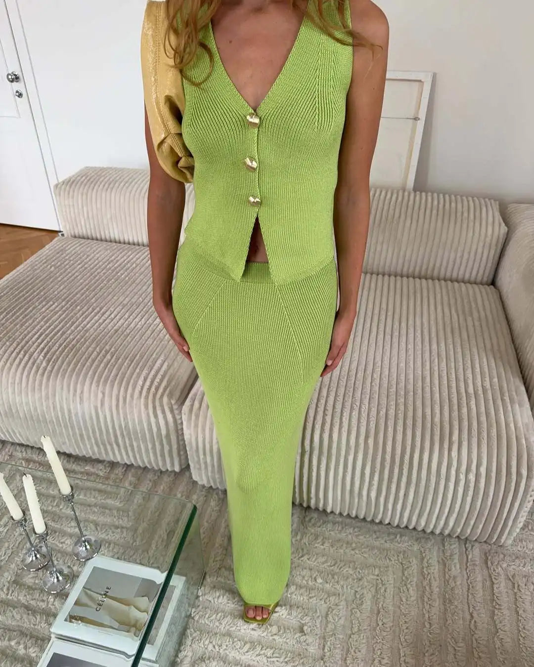 Person wearing a green knitted outfit standing in a living room.