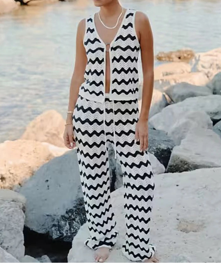Woman wearing a black and white zigzag patterned outfit by a rocky shoreline.