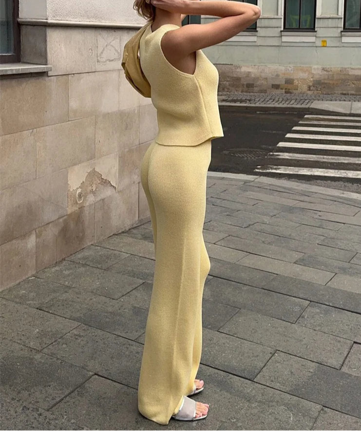 Woman in a yellow outfit standing on a street with a building in the background