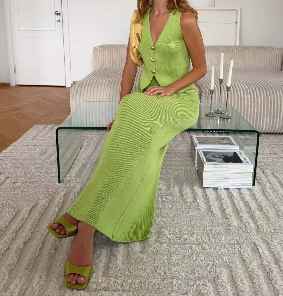 Woman in a green dress sitting on a glass table in a living room.