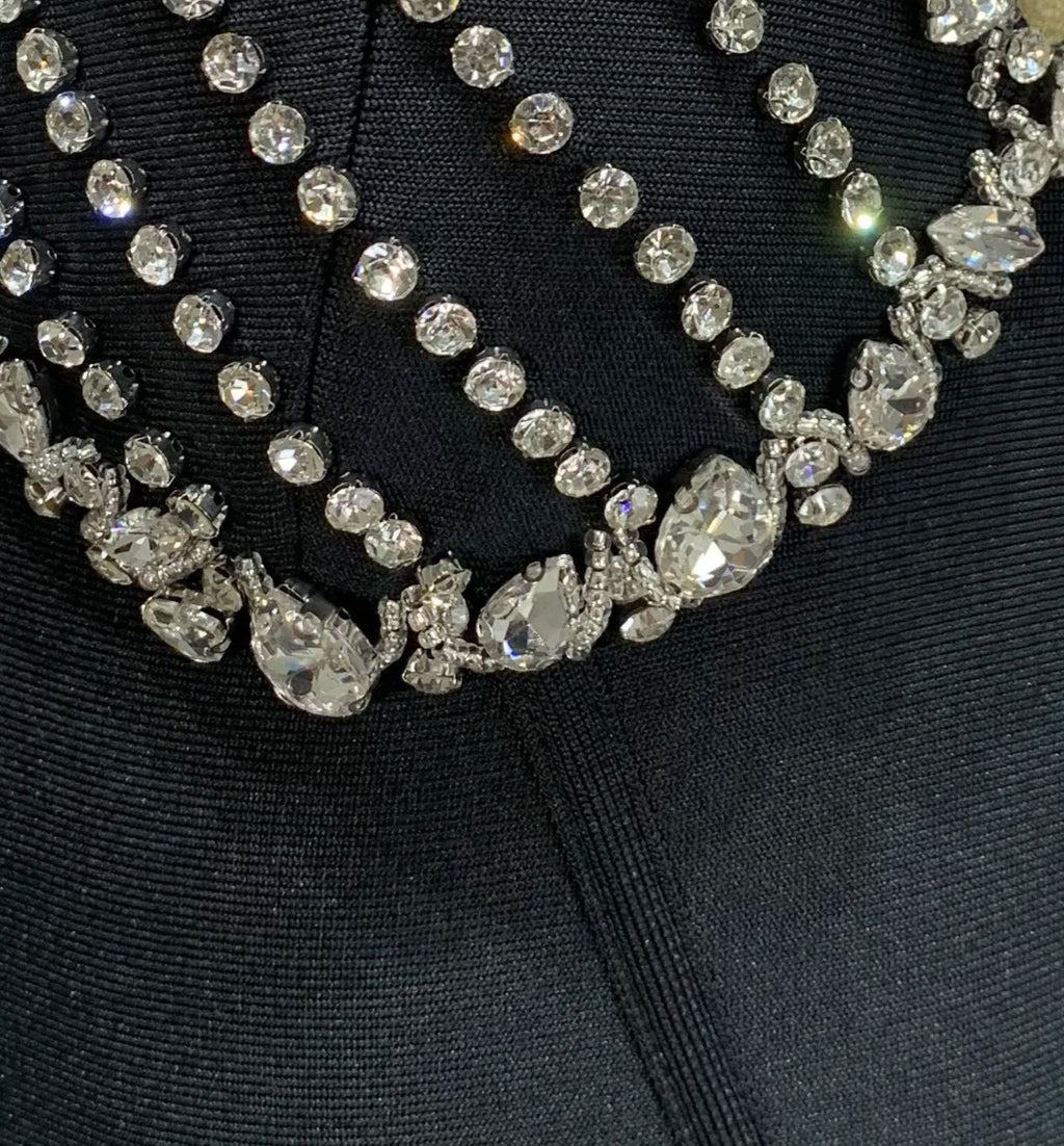 Black garment with a decorative silver brooch on a mannequin against a white background