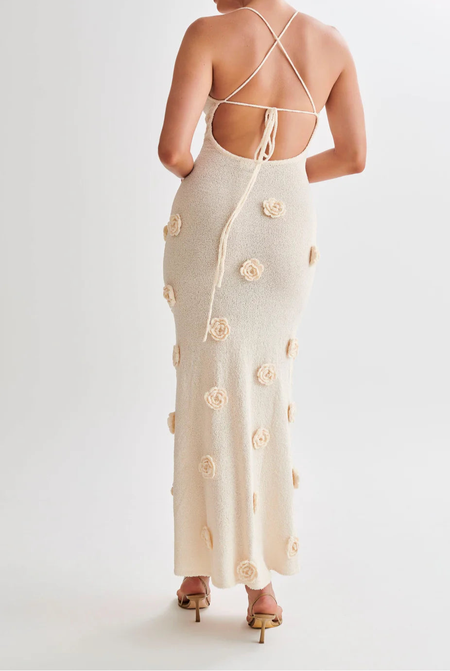 Woman wearing a cream-colored dress with floral patterns on a white background