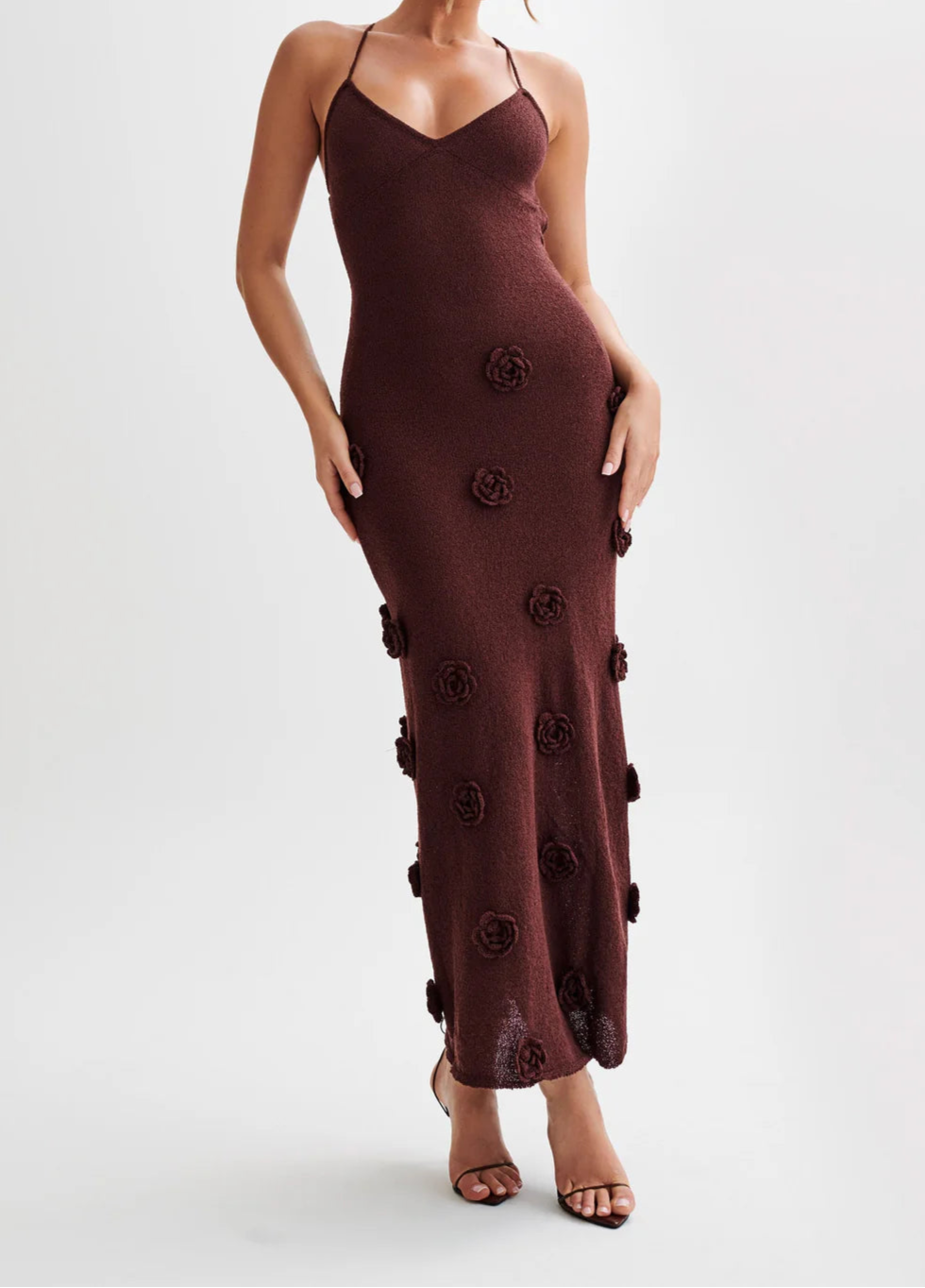 Woman wearing a brown dress with floral embellishments on a white background