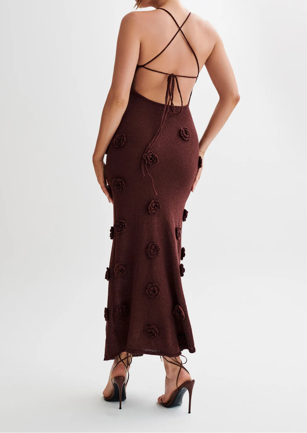 Woman wearing a brown dress with floral details on a white background